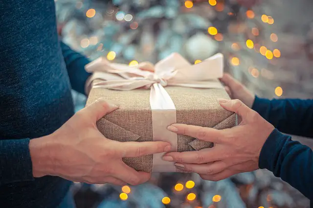 man and woman's hands exchanging wrapped holiday gift